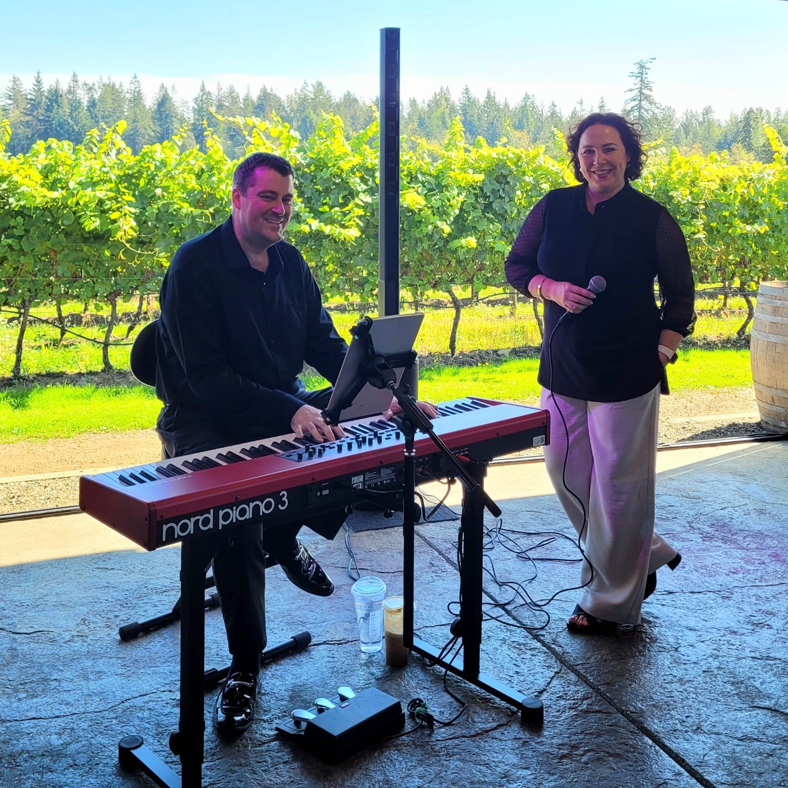 Scott Arkell playing keyboard beside a vocalist at an outdoor vineyard performance
